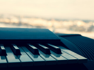 Piano keyboard with blurred background. Black and white keys are covered with dust