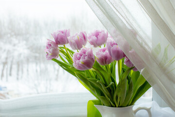 a vase of tulips stands on the window
