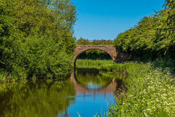 Fototapeta na wymiar A bridge and reflection on the Grand Union Canal near to Great Bowden in summertime