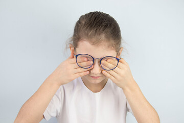 little girl wipes tired eyes from glasses, cute child feeling discomfort and fatigue,tired after long wearing spectacles,eyesight problem,isolated on white background,eye fatigue