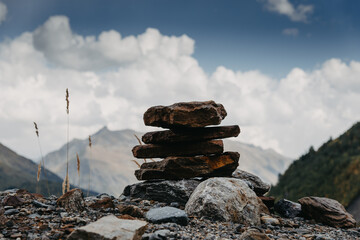 Landmark on the hiking trail - a pyramid of stones on a pass in the mountains against the background of the sky