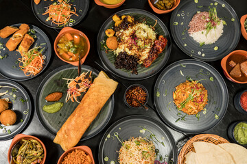 An assortment of Sri Lankan dishes and papadam bread and a chicken dosa in the middle.