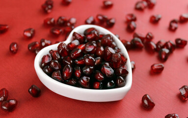 Pomegranate fruits in a plate on a red background