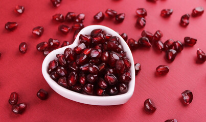 Pomegranate fruits in a plate on a red background