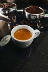 A portafilter with coffee beans, a portafilter with ground coffee, an espresso shot on black table.