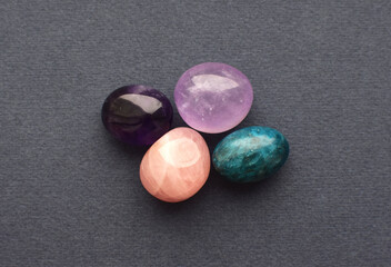 Obraz na płótnie Canvas Multi-colored gemstones, cut tumbling stones. Amethyst, rose quartz, apatite on a gray background.