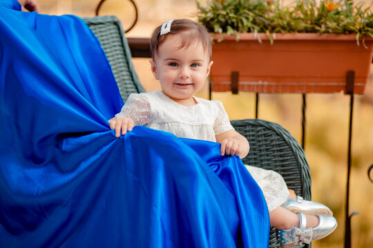 Adorable Baby Sitting On Modern Straw Chair With Blue Fabric And Smiling