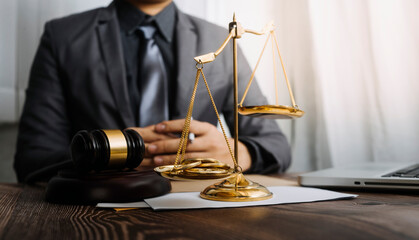 Justice and law concept.Male judge in a courtroom with the gavel, working with, computer and docking keyboard, eyeglasses, on table in morning light