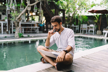 Young man with laptop on poolside