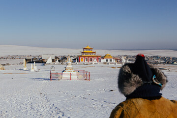 Woman in traditional winter dress is standing in front of Buddist monastery