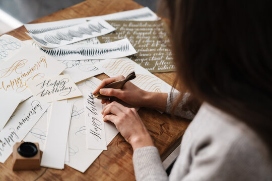 Focused calligrapher girl writing while working at table