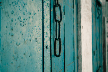 An old style wooden door with a hanging chain as doorknob