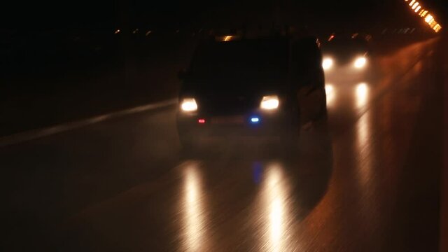 Police cars are chasing an intruder's car in the hard rain. Outdoor front view of police traffic auto driving.