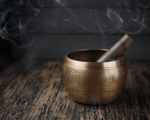 Tibetan singing bowl on sharpen wooden table with smoke around