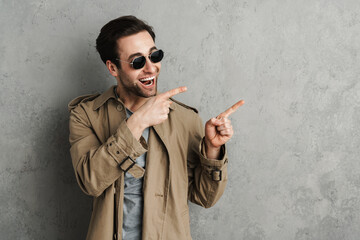 Smiling attractive stylish man in casual outfit pointing fingers