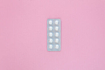 Top view of white pills on pink background, health and vaccination concept. Copy space.