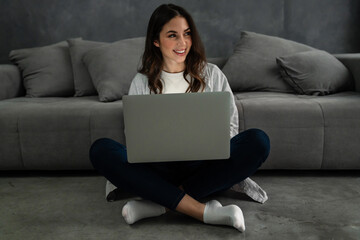 Happy smiling woman sitting on couch and using laptop