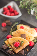 thin homemade pancakes with raspberries and chocolate , with herbs, , close-up, vertical arrangement,