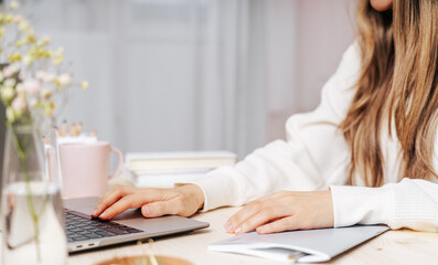 Distance learning online education and work. Business woman writes goals, plans, make to do and wish list in notebook on desk, working from home office. Using laptop.