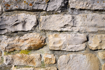 Background of a wall made of natural stones that have been machined and put on top of each other with mortar that is old.