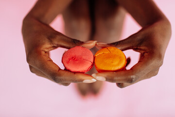 Macaroon cookies on a pink background in the hands of an african american woman