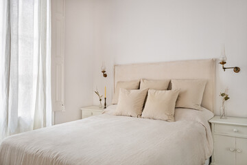 Bright bedroom interior, cozy bed with pillows, beige linen, vintage lamps and dry flowers on a...