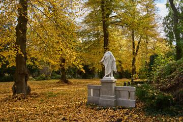 Grabmal mit beschädigter Statue einer Frau, Bäume im Herbstlaub, Luisenstädtischer Friedhof, Kreuzberg, Berlin, Deutschland