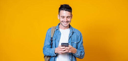 Isolated young man using mobile smart phone on a yellow background - Millennial holding cellphone - People and technology concept
