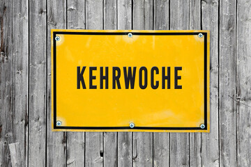 Schild Kehrwoche vor Holz Hintergrund.