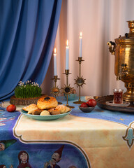 Beautiful Novruz table set up in blue with semeni, wheat grass, sweets and dry fruits and festive candles with tea and golden samovar.