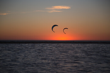 Persons engaged in Kite-surfing during sunset on Atlantic ocean. Two kite-surf wings on the air on...
