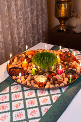 Novruz traditional tray with green wheat grass semeni or sabzi, sweets and dry fruits and festive candles with tea. Traditional celebration of spring equinox in March in Azerbaijan 