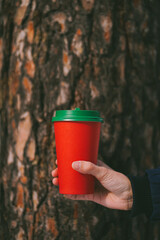 Red paper cup with green lid on tree trunk background. Recycle concept. Safe the planet. Earth day concept