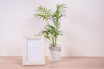 Portrait white picture frame mockup on wooden table. White wall background. Scandinavian interior. 

