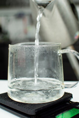 Bubbles in hot water boiling inside glass transparent teapot. Close up of boiling water in transparent kettle on kitchen scales. Splashing water bubble background.