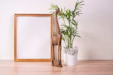 Portrait broun picture frame mockup on wooden table. Wooden decor giraffe figure and palm. White...