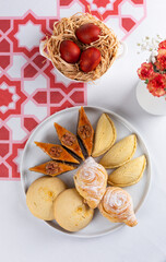 Beautiful Novruz table set up with national pastry in white plate with dyed red eggs and flowers in red and white colors. Celebration of spring equinox in Azerbaijan in March. Flat lay  copy space