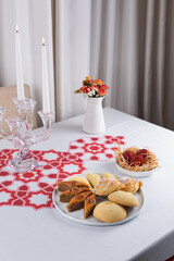 Beautiful Novruz table set up with national pastry in white plate with dyed red eggs and flowers in...