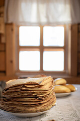 Pancakes in a wooden house on the background of a window.