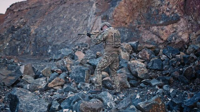 Soldier in full protection with an assault rifle moves in the gorge participating in a special operation.
