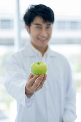 Green apple is held by smart scientist man in laboratory or classroom with concept of healthy fruit...