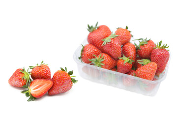 Fresh organic ripe strawberries in a plastic tray, whole and half rotated isolated on white background.