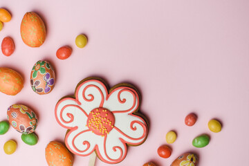 Easter gingerbread, sweet colored candies and small, decorative eggs on a pink background. Easter card