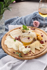 different cheese platter with honey and glass of white wine in the table