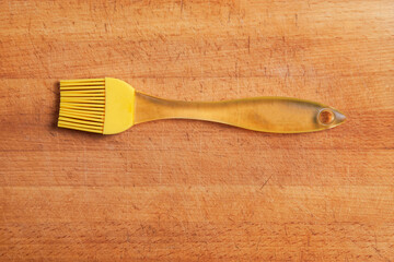 A yellow kitchen silicone brush sits on the cutting board