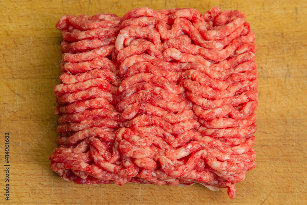 Wall mural Red minced beef with chunks of fat on a chopping board