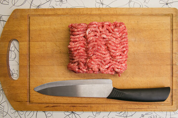 Ground beef and a knife are on the cutting board