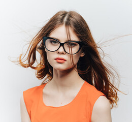 Obraz premium pretty woman in orange sundress and glasses on a light background cropped view