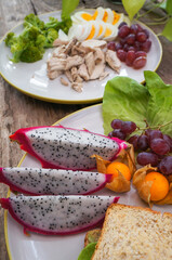 Dragon fruit, grape, grape, whole wheat bread, boiled chicken breast and boiled egg, broccoli in a healthy vegetarian dish. 