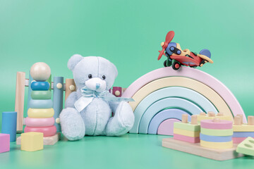 Kids toys collection. Teddy bear, wooden rainbow, plane, educational and music baby toys on light green background